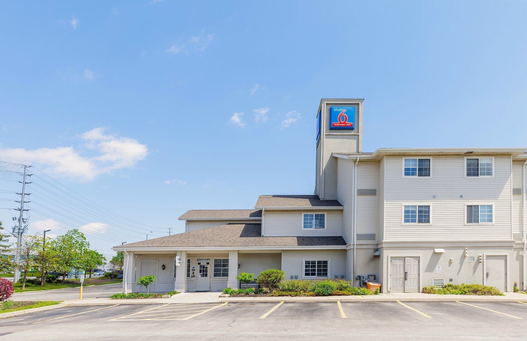 Un motel avec une enseigne bien visible indiquant « studio », un parking et un aménagement simple et fonctionnel.