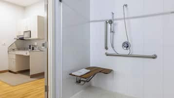 A modern bathroom with a shower, grab bar, and a small bench.