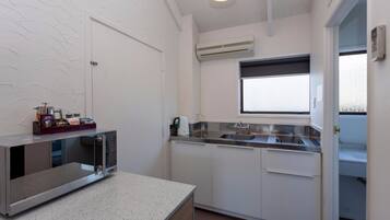 A compact kitchen with a microwave, sink, and window.