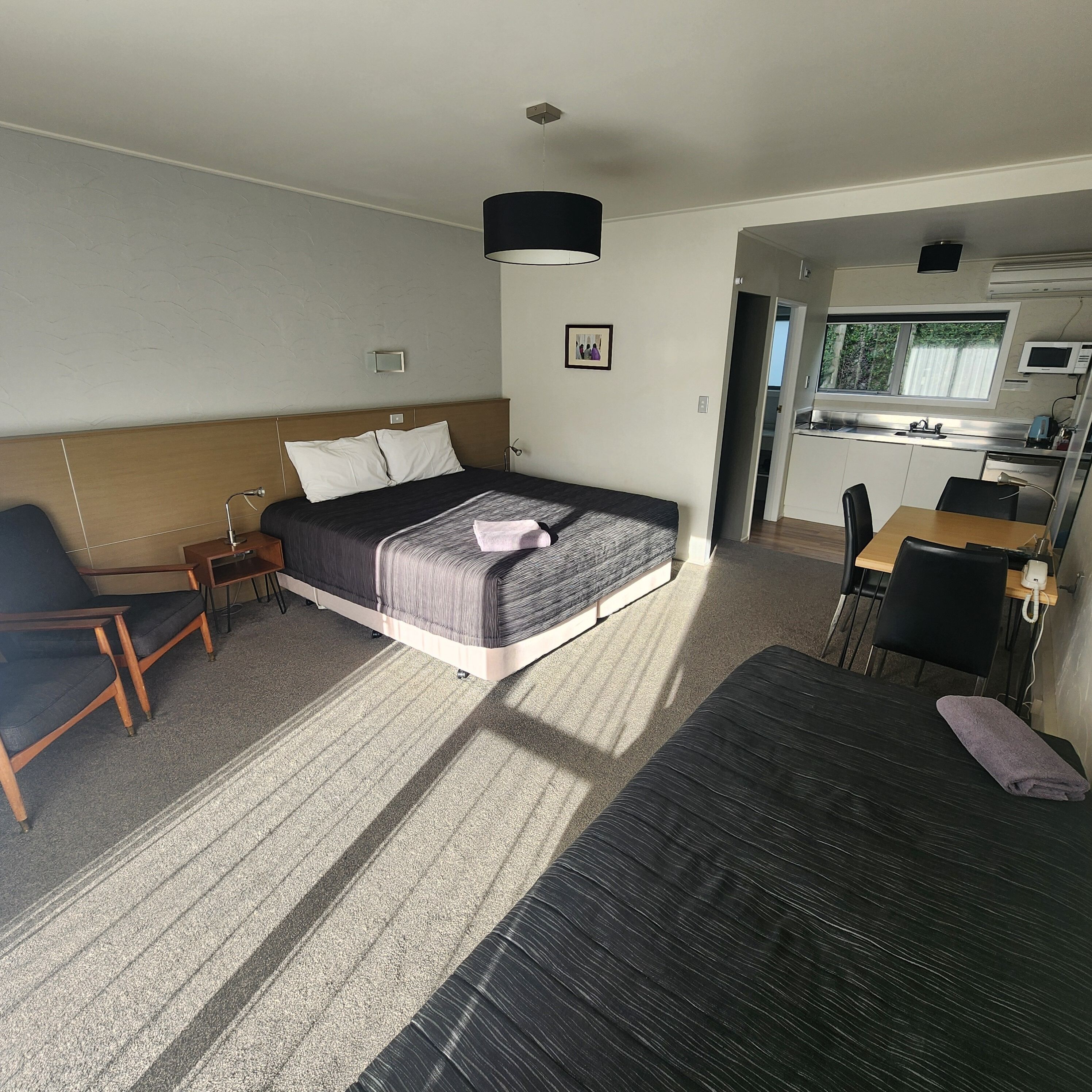 Una habitación de hotel con cama, escritorio, silla, sofá y kitchenette.
