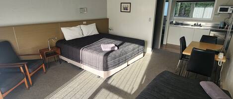 Una habitación de hotel con cama, escritorio, silla, sofá y kitchenette.