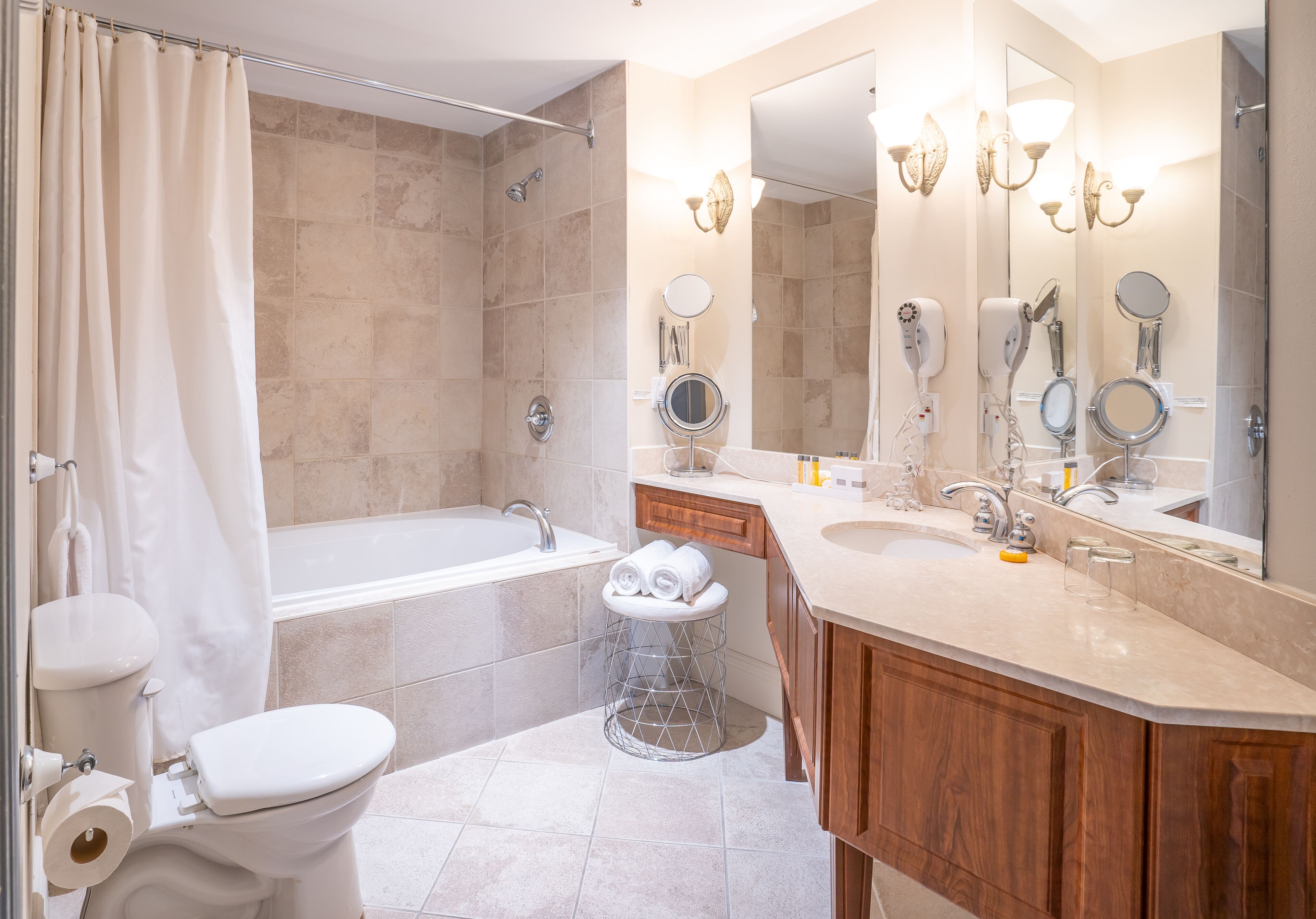 A modern bathroom with a bathtub, a toilet, a sink, and a vanity with a mirror.