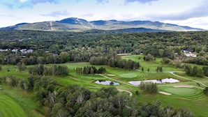 A golf course with multiple holes, water hazards, and a mountainous backdrop.