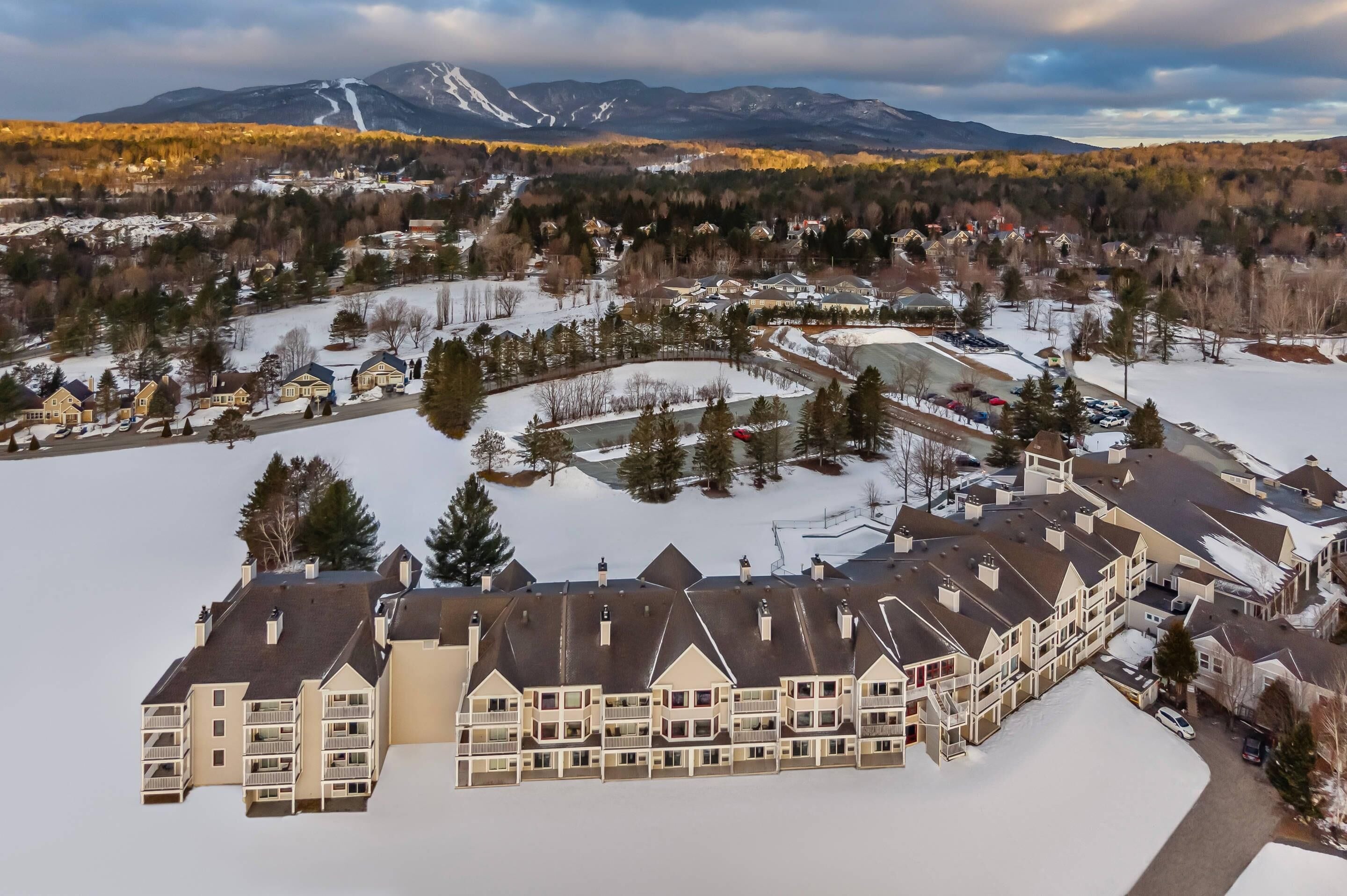 A multi-story hotel with a central courtyard, surrounded by snow-covered grounds and mountains in the background.