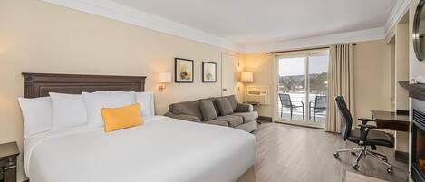 Una habitación de hotel con una cama grande, un sofá, un escritorio y una chimenea.