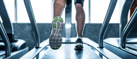 A treadmill with metal handrails and a person using it.