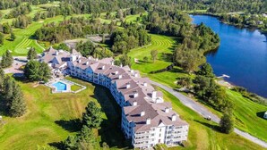 A large hotel with multiple buildings, a swimming pool, and a golf course nearby.