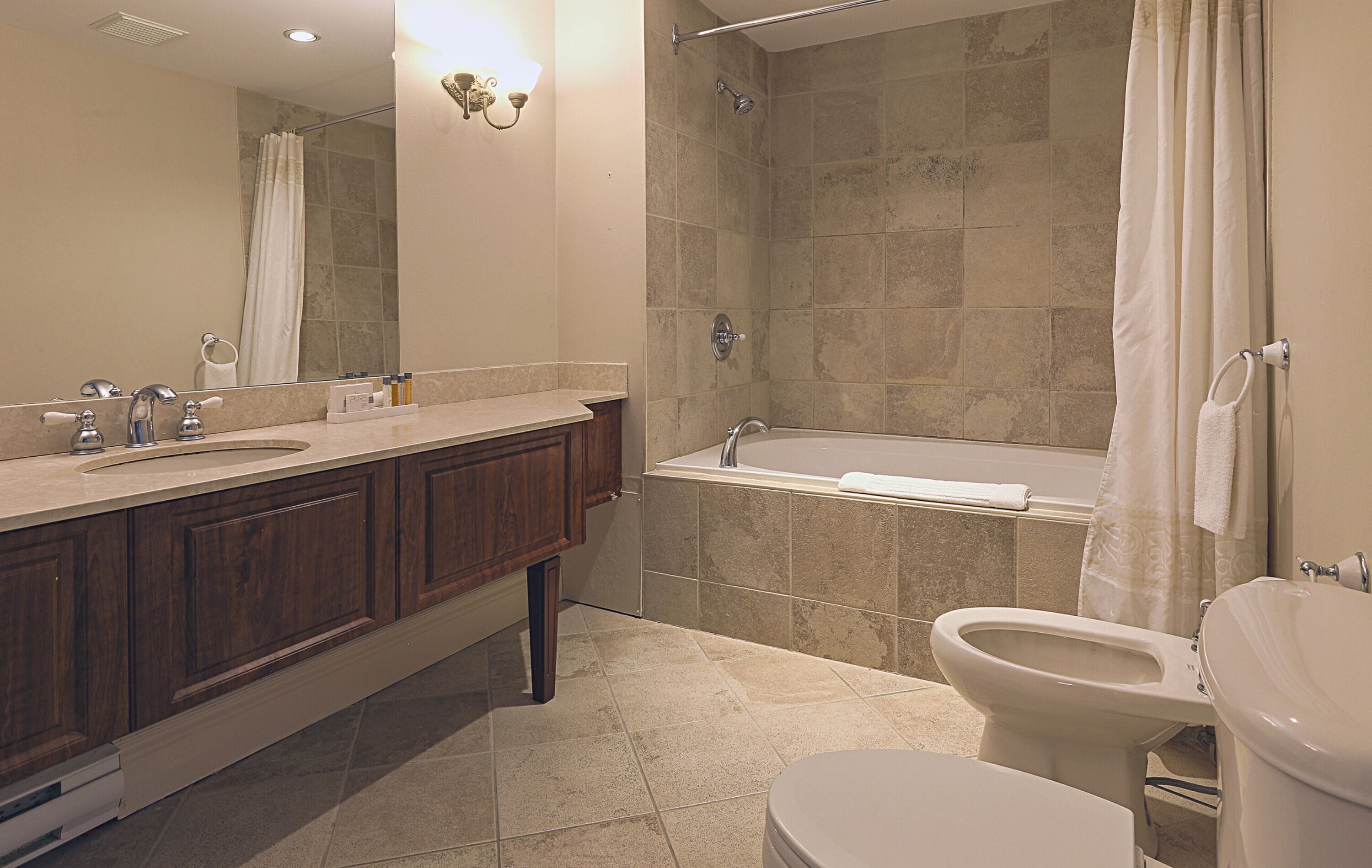 A bathroom with a sink, vanity, bathtub, and toilet.