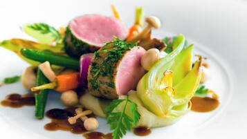 Un plat composé de différentes sortes de légumes et d’une tranche de viande, probablement du porc, le tout agrémenté d’herbes aromatiques.