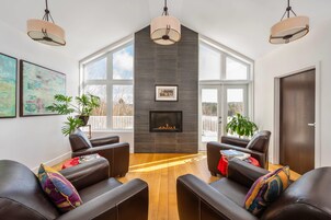 Una sala de estar moderna con sofás de cuero, chimenea, ventanas amplias y obras de arte en las paredes.