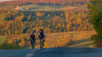 Two cyclists on a road with a hilly landscape in the background.