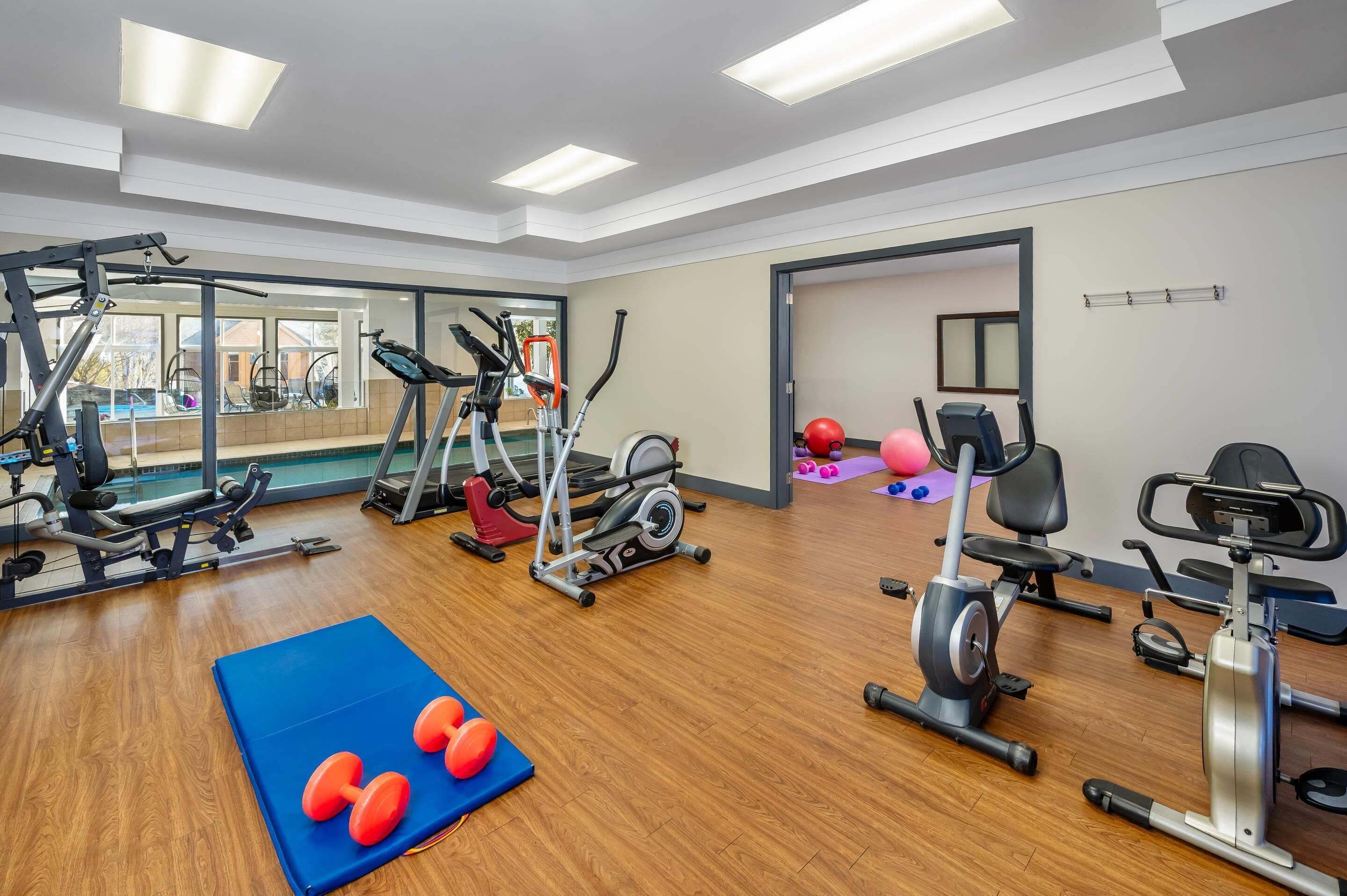 A gym with various exercise equipment, including treadmills, stationary bikes, and free weights.