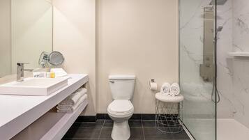 A modern bathroom with a white sink, toilet, and glass-enclosed shower.