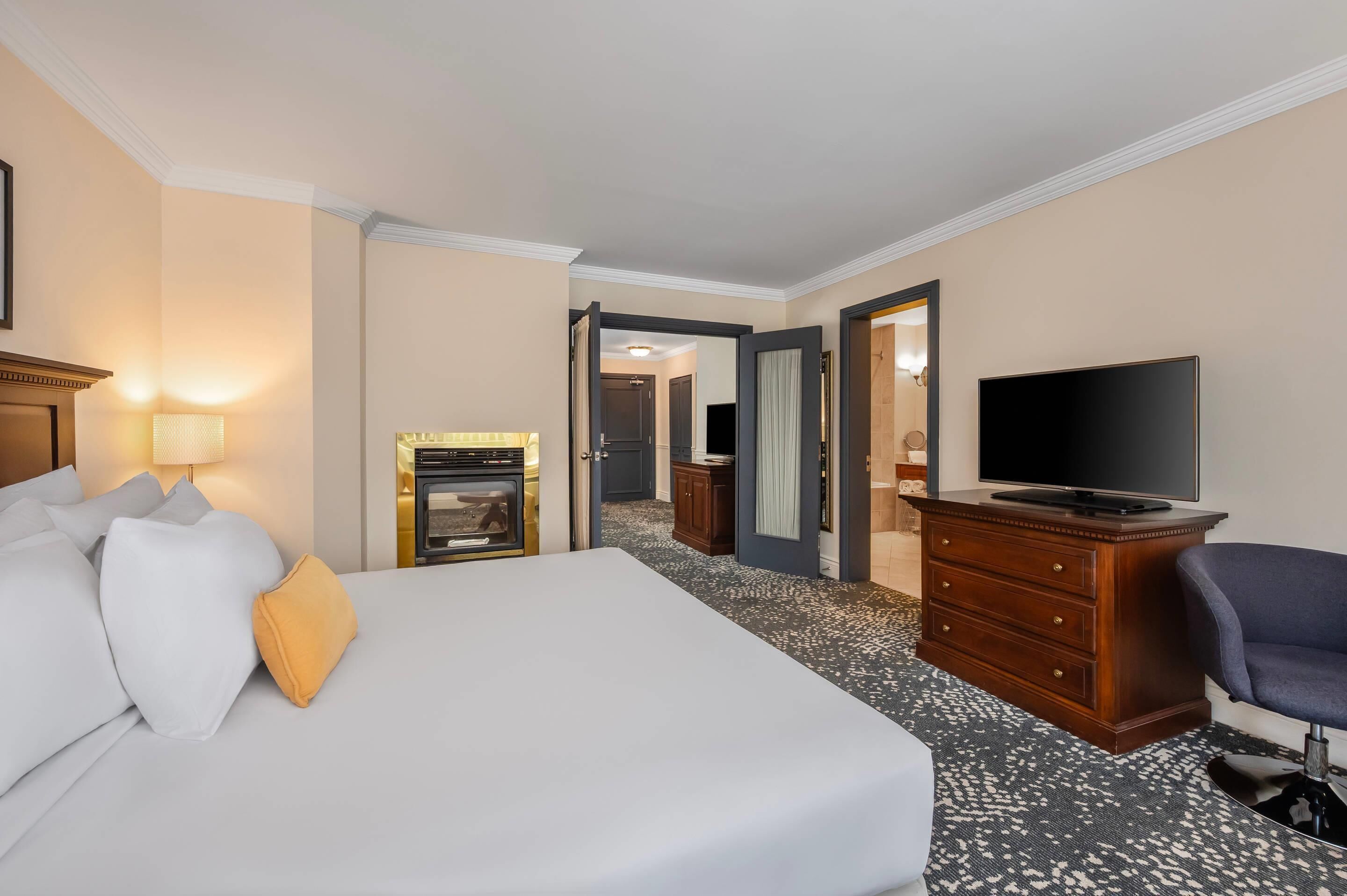 A hotel room with a bed, a television, a dresser, and a mirror.