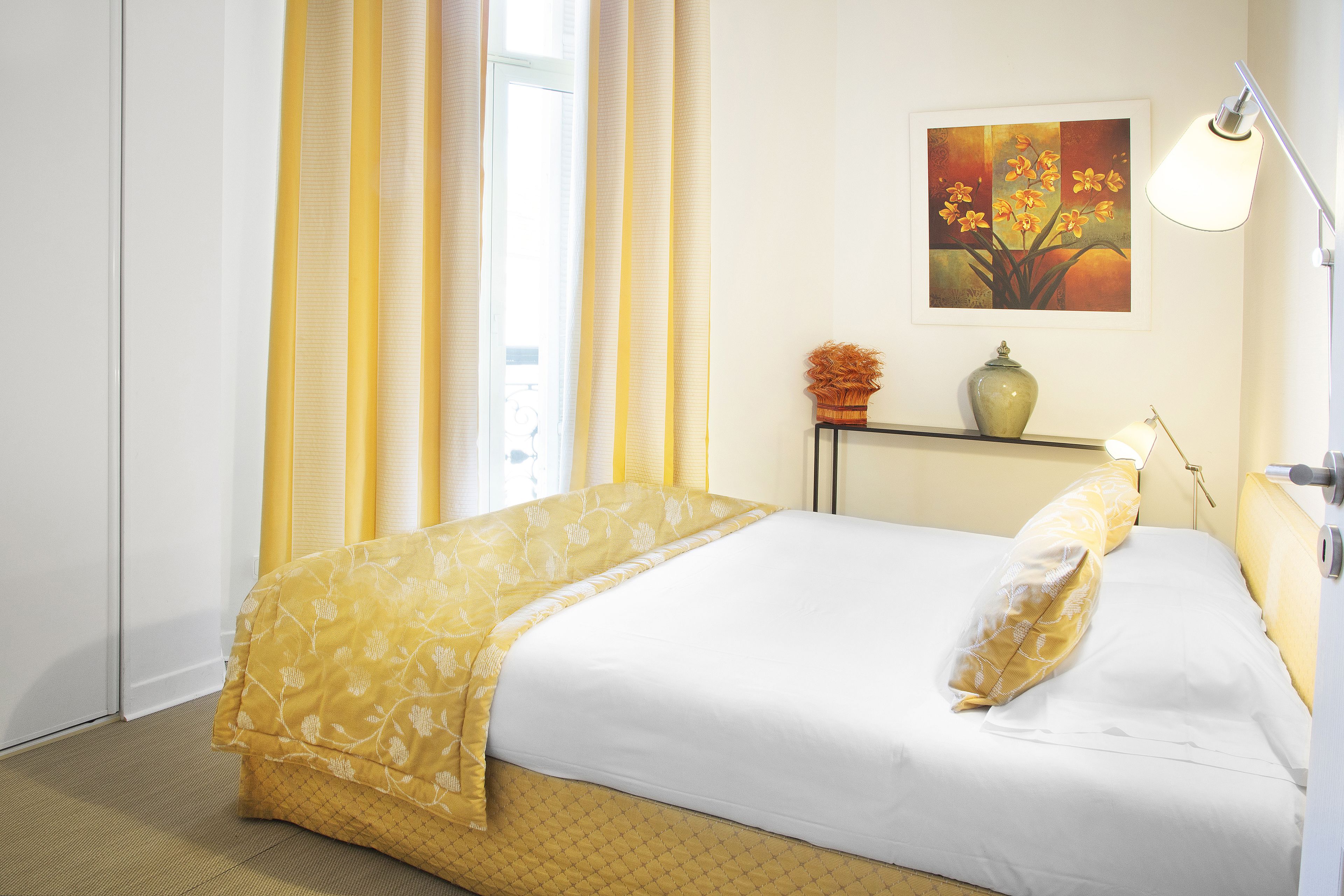 Une chambre d’hôtel avec un lit, un vase et un tableau au mur.