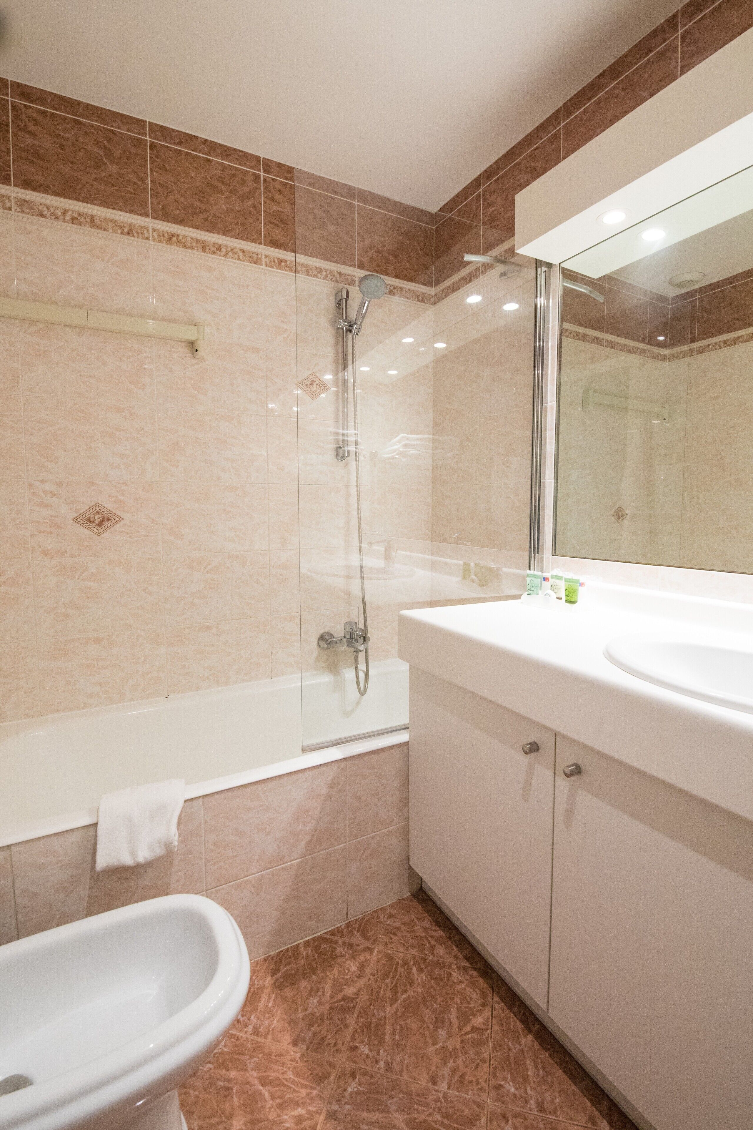 A bathroom with a glass-enclosed shower, a white sink, and a toilet.