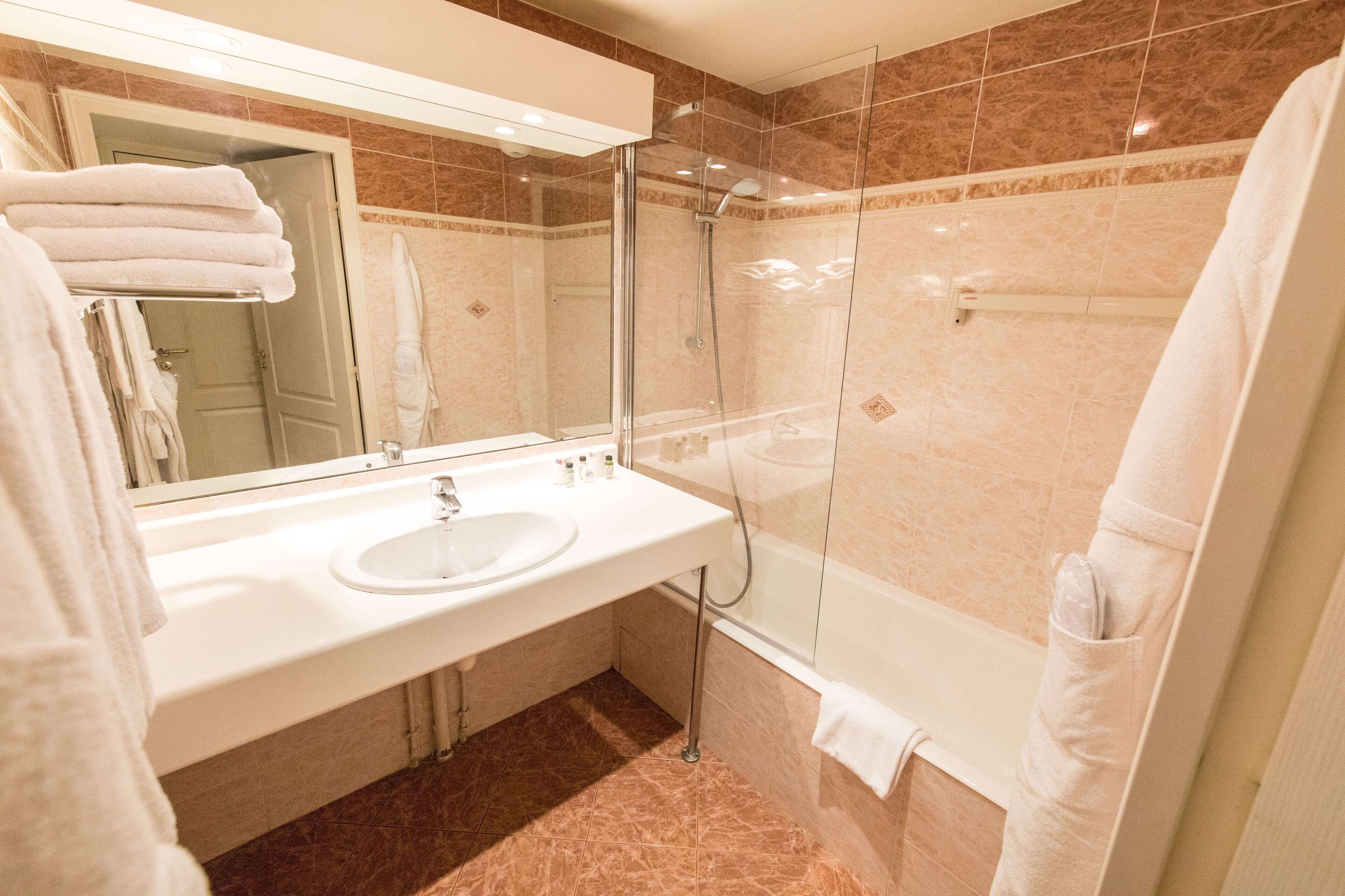 Un baño moderno con ducha envuelta en vidrio, un lavabo blanco y un espejo grande.