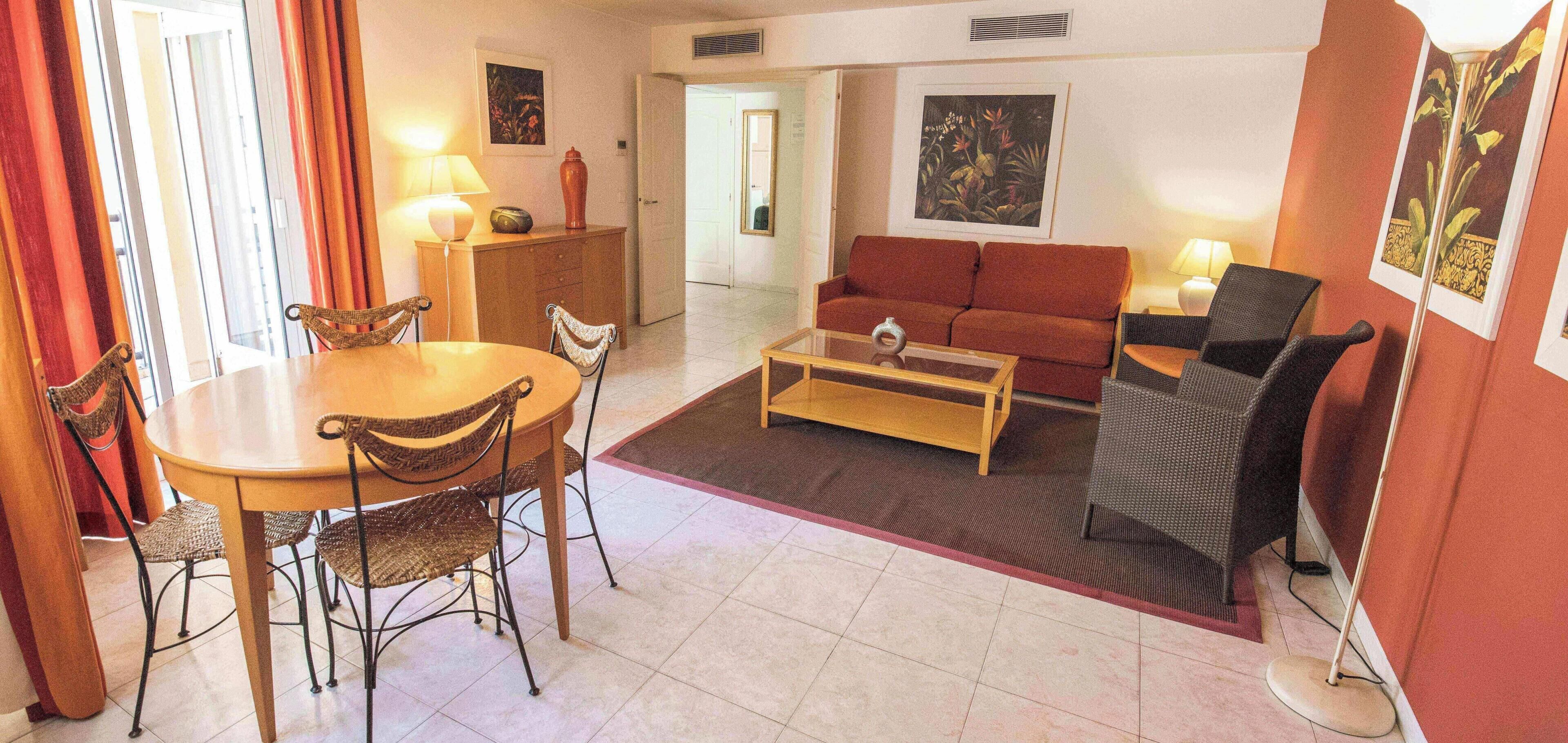 Una sala de estar con sofá, una mesa de centro y un comedor con sillas y una mesa.