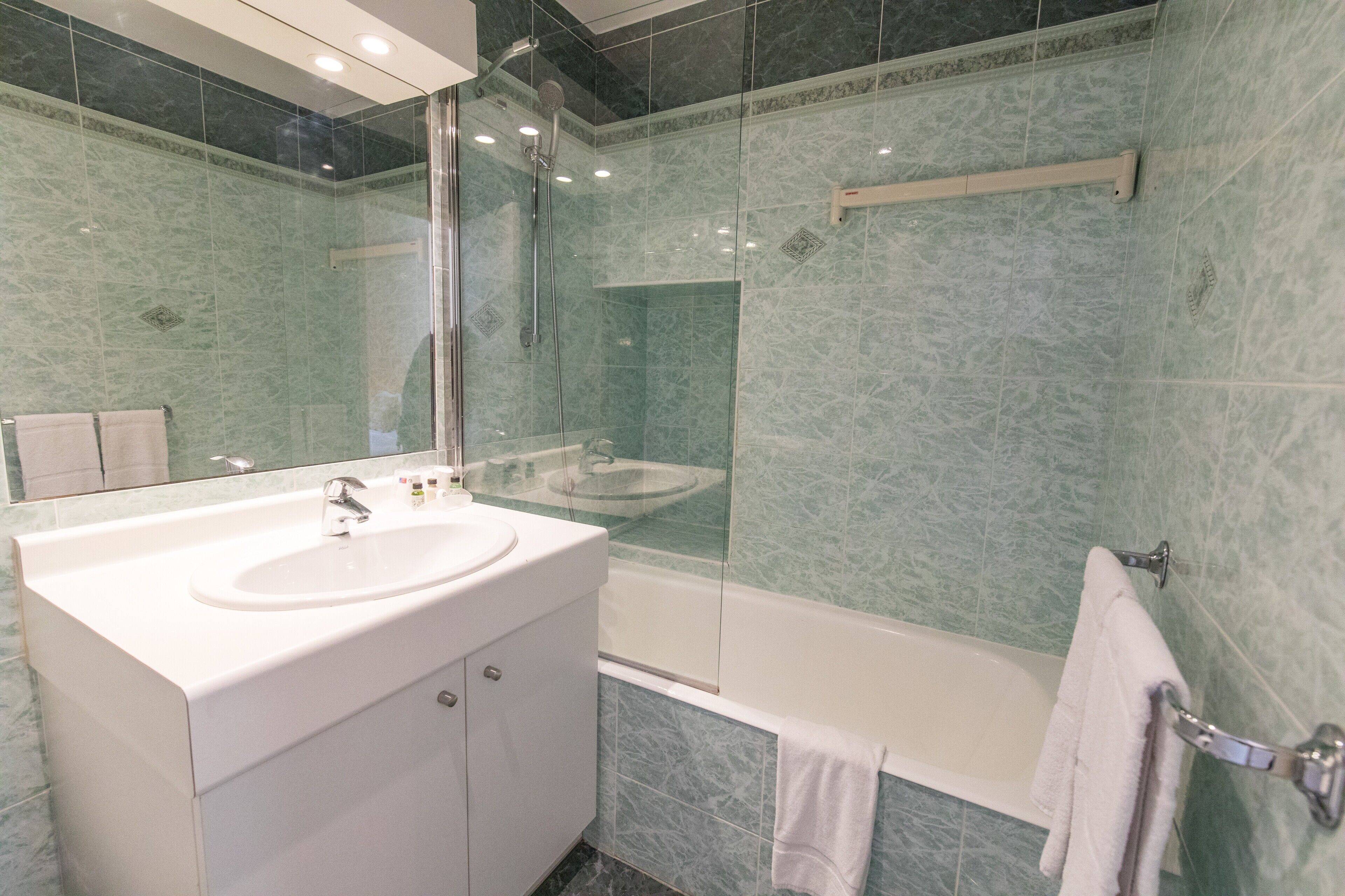 A modern bathroom with a glass-enclosed shower, a white sink, and a bathtub.