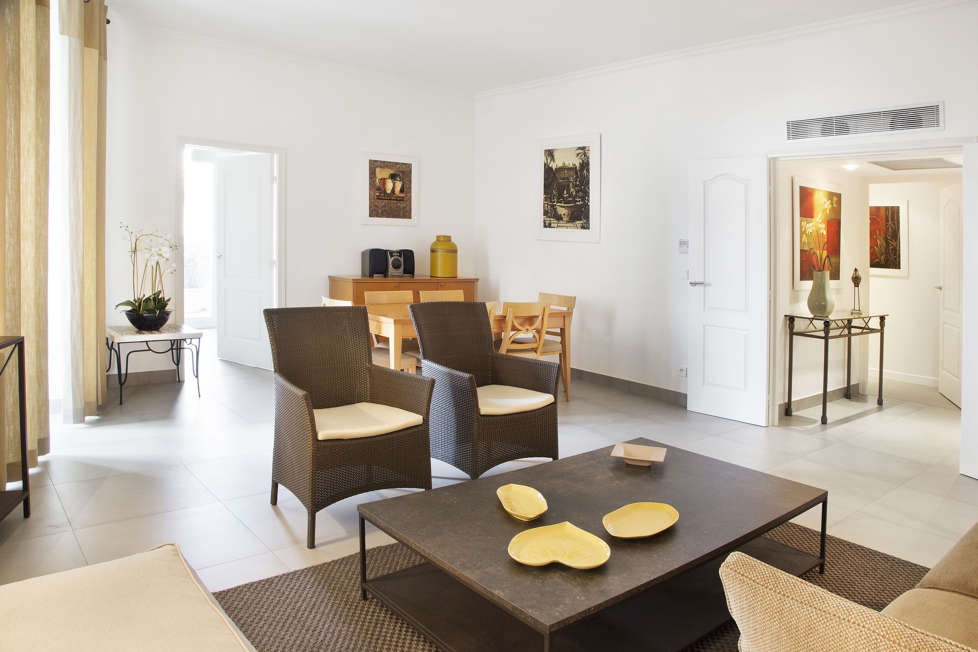 Uma sala de estar moderna com sofá, duas poltronas, uma mesa de centro e um espaço de jantar com cadeiras e uma mesa.