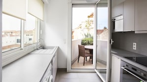 A compact kitchen with a washing machine, a dining area with a table and chairs, and a view of the neighborhood through a sliding door. - Cannes Croisette Prestige (Cannes)