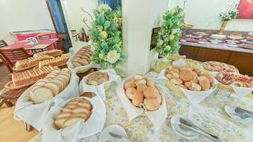 A buffet table with various breads and pastries, surrounded by floral decorations.