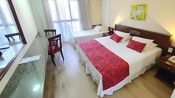 A hotel room with two beds, a dining table, and chairs.