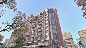 Un hotel moderno con una fachada de vidrio destacada, varios balcones y una entrada visible.
