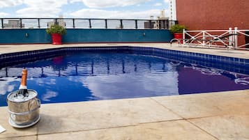 Una piscina al aire libre, sombrillas, sillones reclinables de piscina