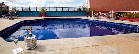 Una piscina al aire libre, sombrillas, sillones reclinables de piscina
