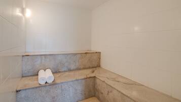 Steps lead to a shower area with a bathtub, towels at the ready.