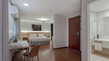 Et moderne hotelværelse med seng, natbord og skrivebord med stol.