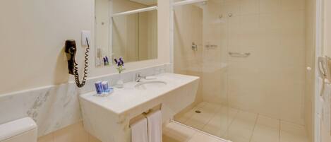 Un baño con lavamanos blanco, espejo y ducha.