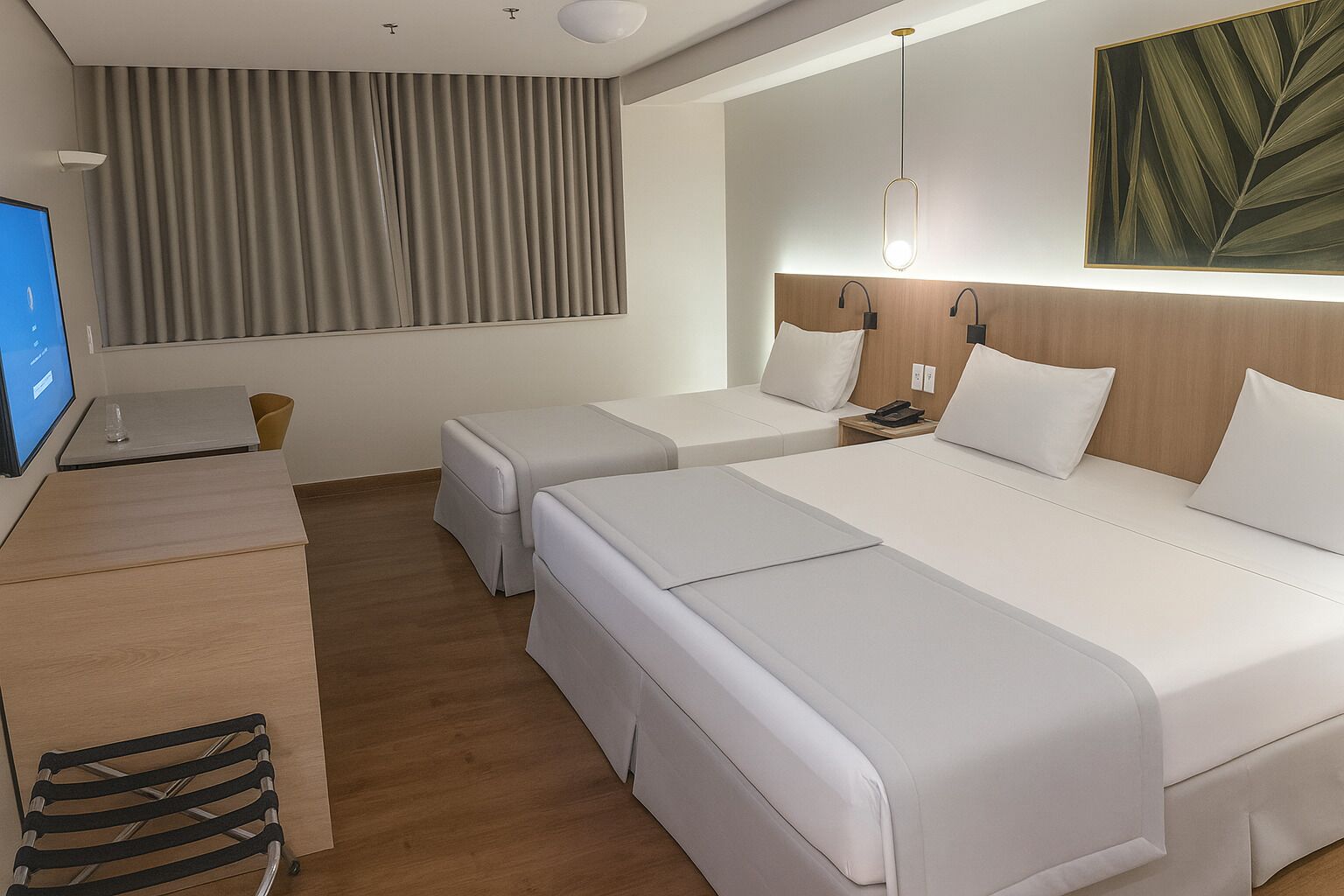 A hotel room with a bed, bedside tables, a desk, and a TV.