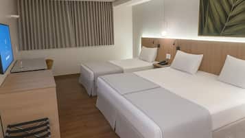 A hotel room with a bed, bedside tables, a desk, and a TV.