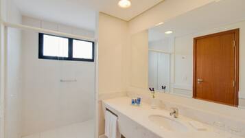 Un baño moderno con cabina de ducha, un espejo grande y un lavamanos blanco.