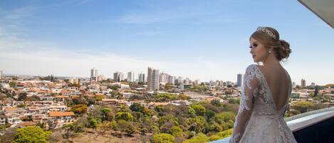 A person in a wedding dress overlooking a cityscape with buildings and greenery.