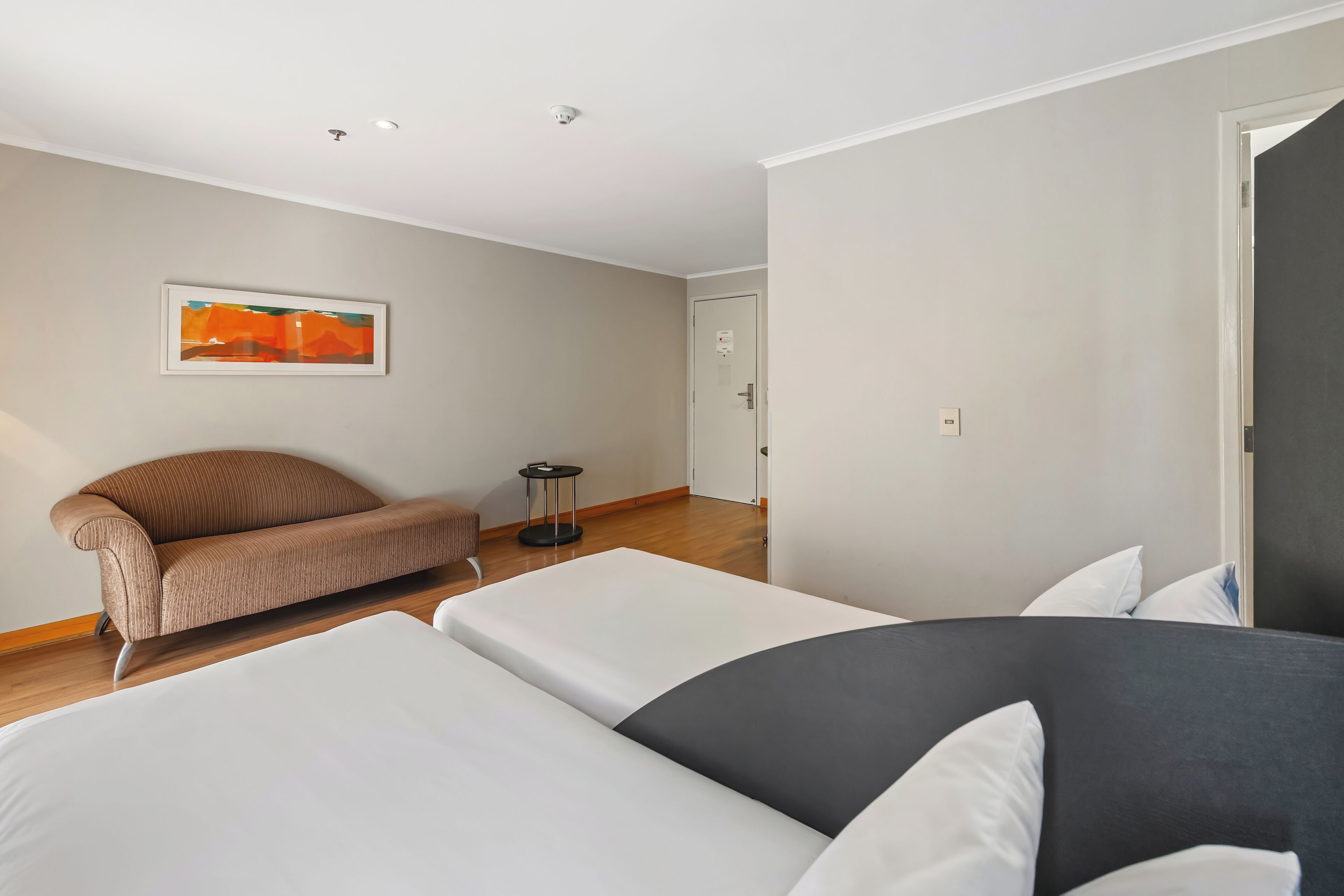 Una habitación de hotel moderna con una cama grande, un sofá y una mesita.