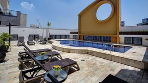 A rooftop pool area with lounge chairs and a circular architectural feature. - SLAVIERO São Paulo Ibirapuera (São Paulo)
