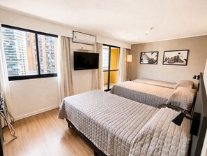A hotel room with two beds, a TV, a window with a view of buildings, and a flat-screen TV mounted on the wall. - SLAVIERO São Paulo Ibirapuera (São Paulo)