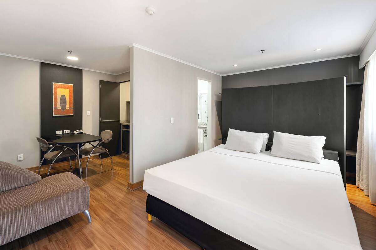 Een hotelkamer met een groot bed, een bureau met stoelen en een kleine zithoek.