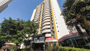 A tall, multi-story building with a yellow and white facade, featuring a prominent entrance with steps and a glass facade. - SLAVIERO São Paulo Ibirapuera (São Paulo)