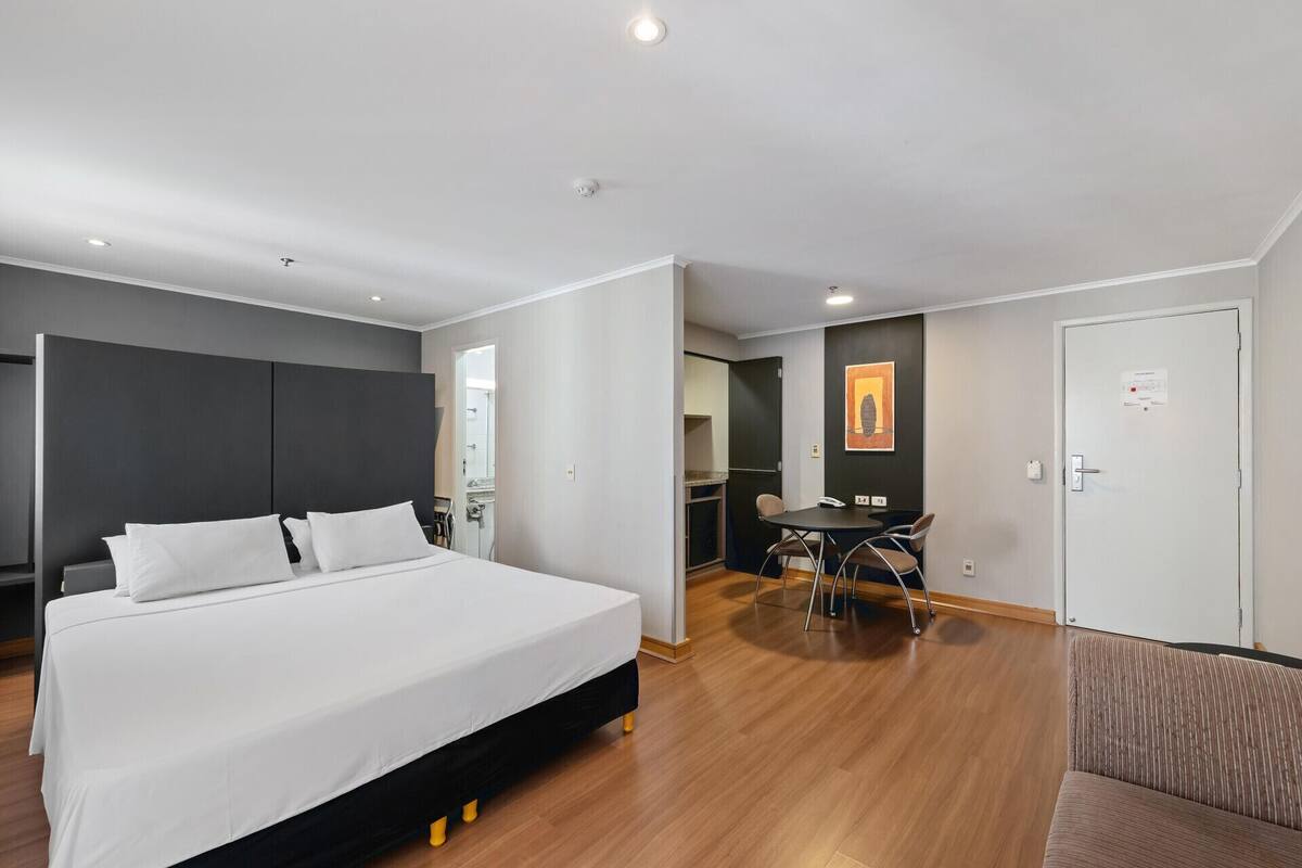 Een moderne hotelkamer met een groot bed, een eettafel en een aparte zithoek.