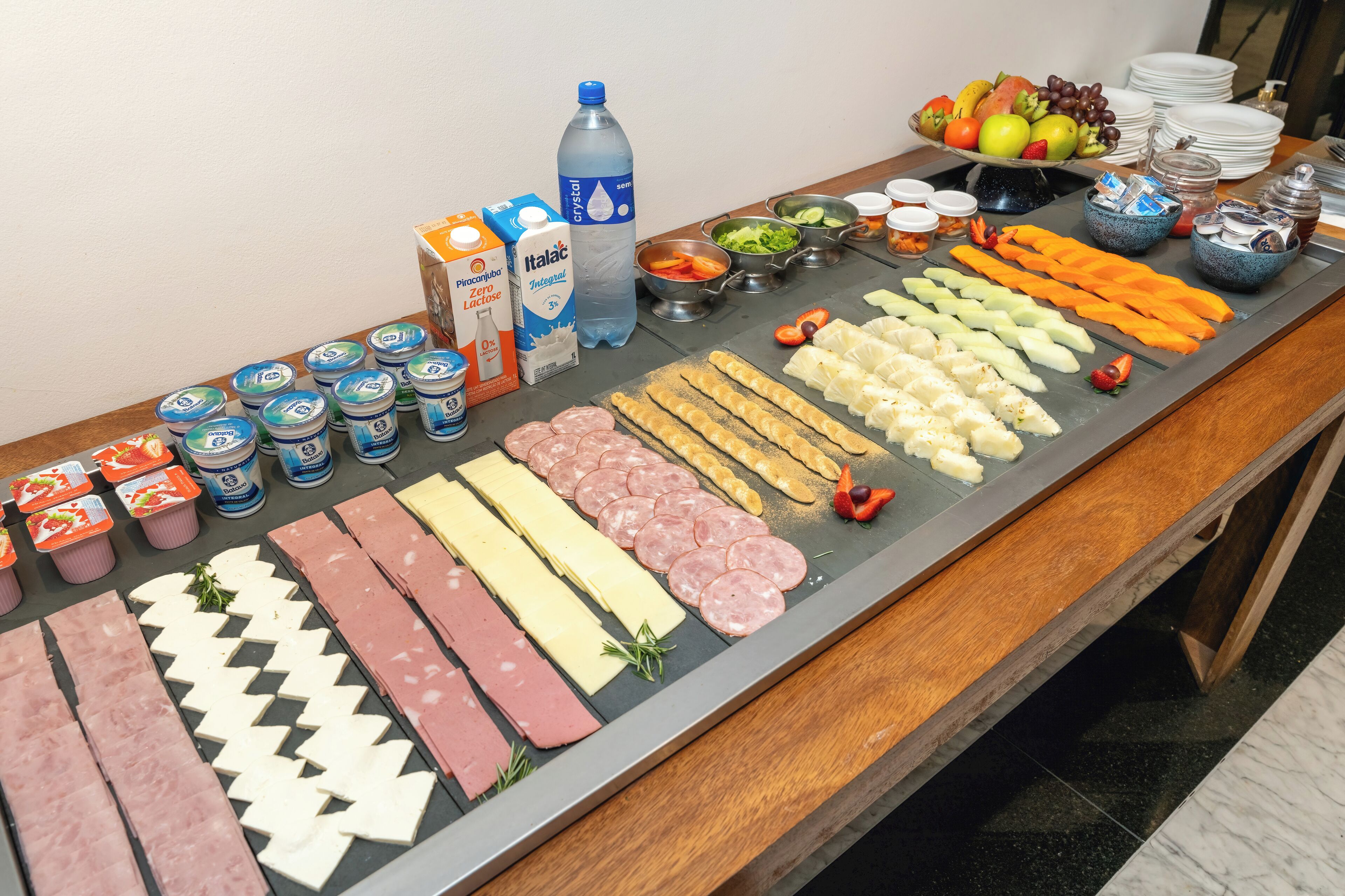 A buffet table with various food items including meats, cheeses, and fruits.