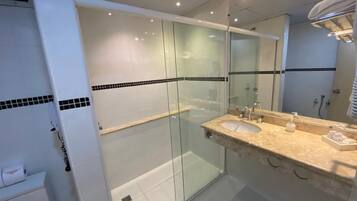 Une salle de bain moderne avec une douche à parois de verre, un lavabo avec un miroir et un porte-serviettes.
