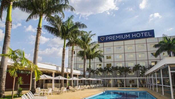 A hotel with a swimming pool, lounge chairs, and palm trees. - Hotel Premium Campinas (Campinas)