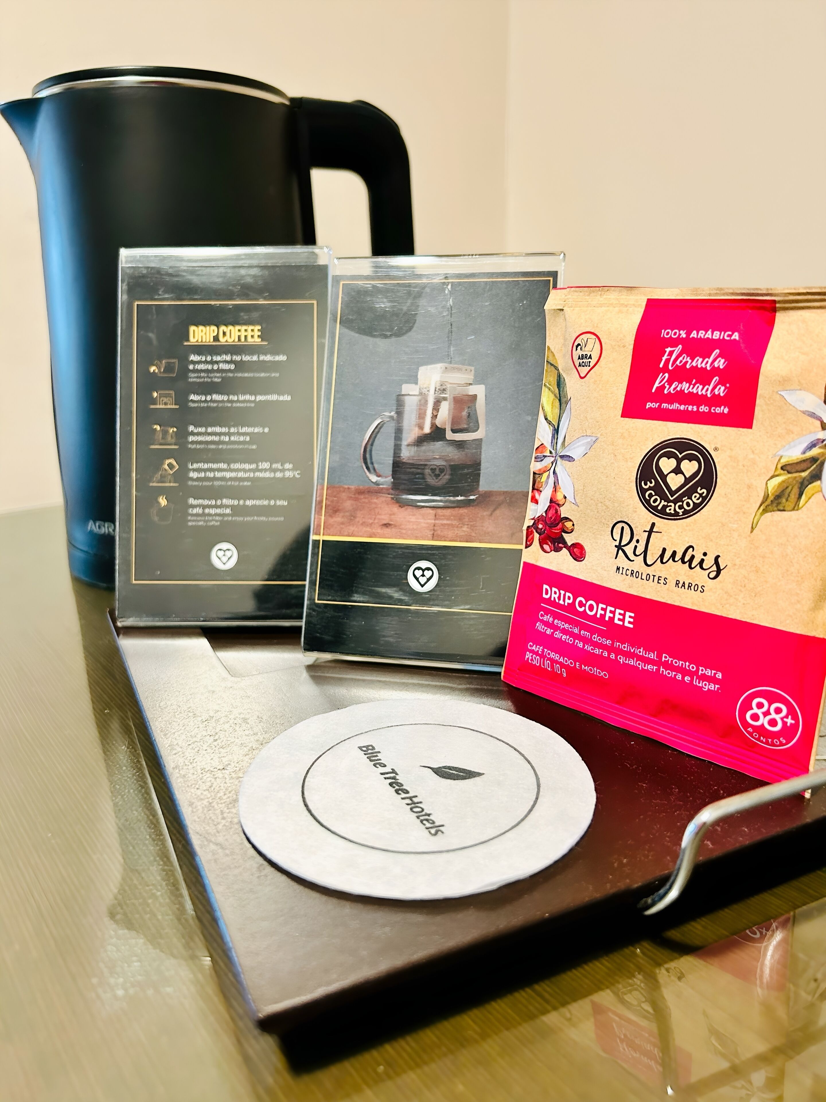 A drip coffee maker, a coffee bag, and a coffee pod on a table.