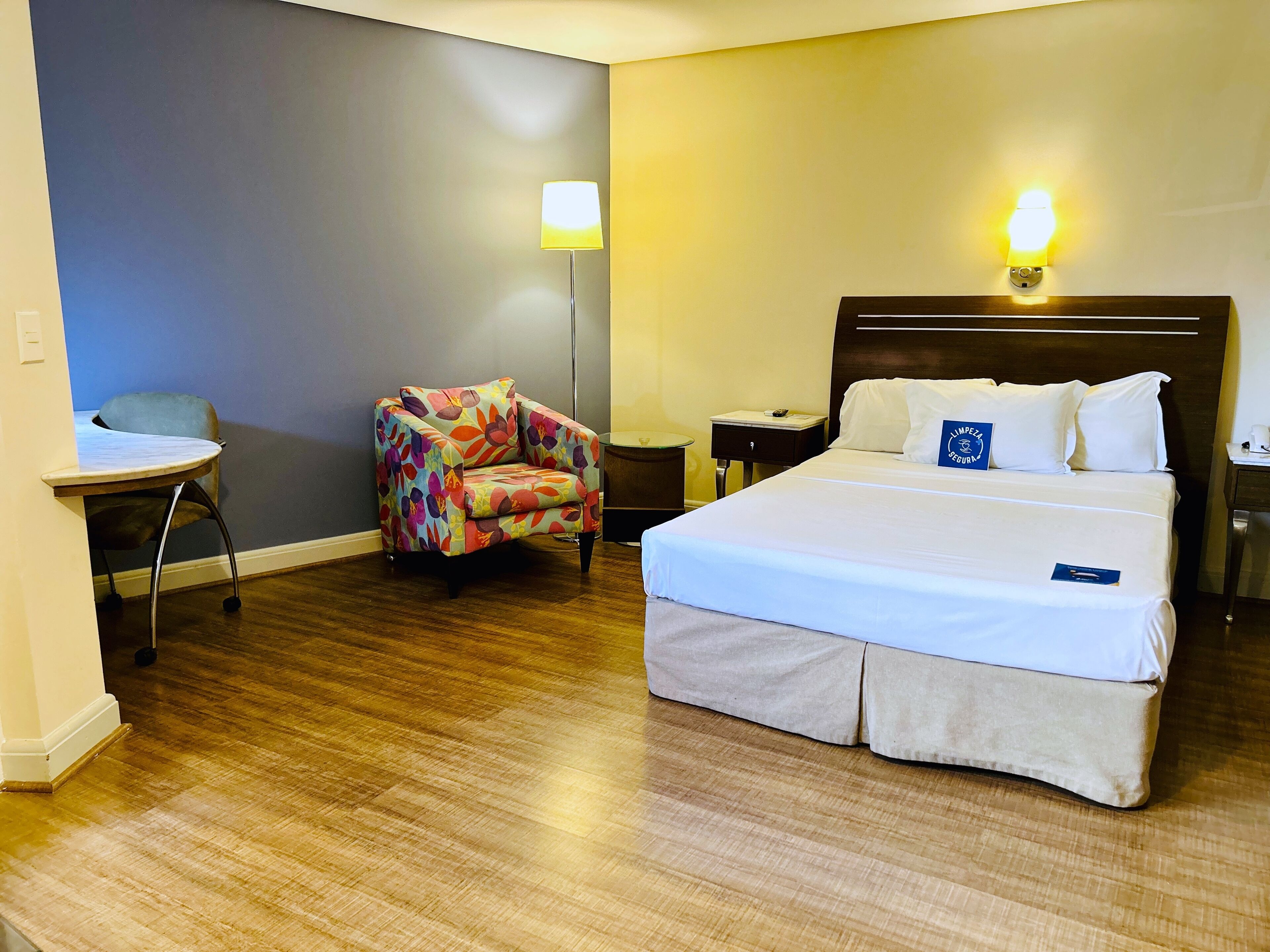 Une chambre d’hôtel avec un lit, une chaise, une table de chevet et une lampe.