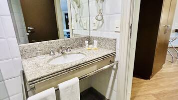 Un baño moderno con dos lavamanos, un espejo y un secador de pelo montado en la pared.