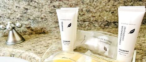 A bathroom counter with toiletries including a shampoo and conditioner tube, a shower cap, and a bar of soap.